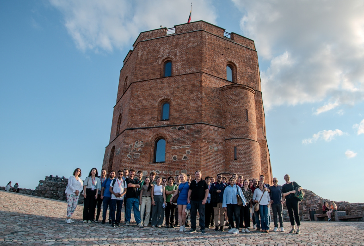 Mokyklos dalyviai ir dėstytojai prie Gedimino pilies bokšto Vilniuje. Organizatorių nuotrauka.